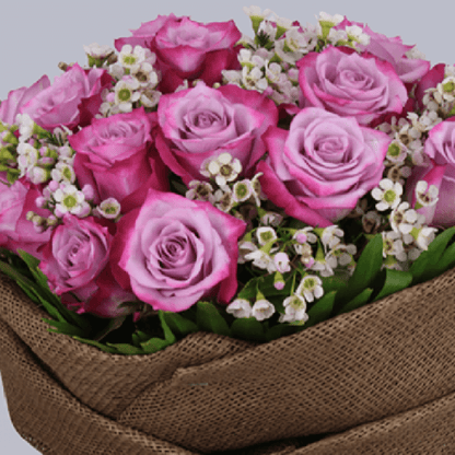 Purple roses with small wax flowers wrapped in brown jute and finished with natural raffia