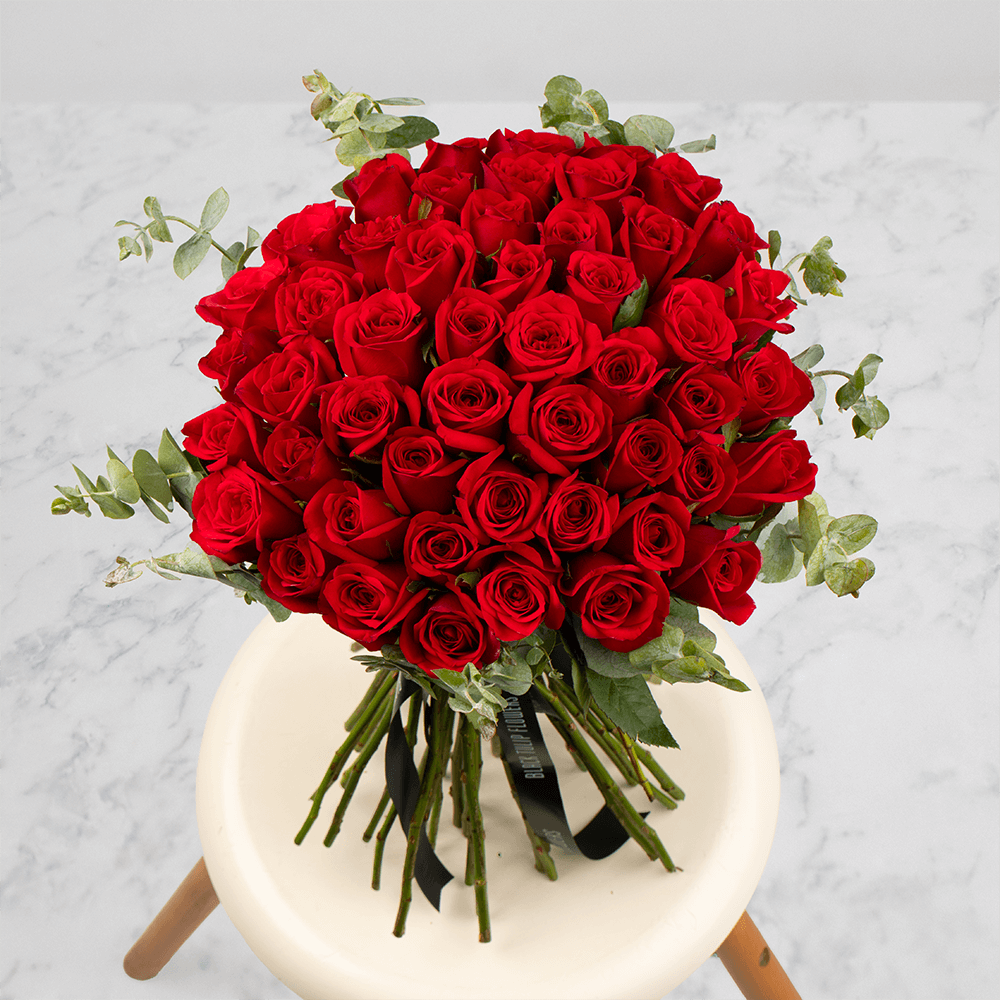 Hand-tied bouquet of 50 red Roses with fresh Eucalyptus foliage.