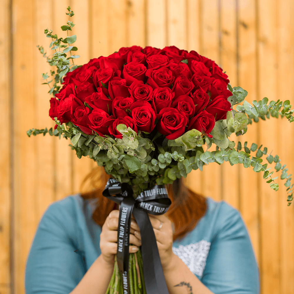 Hand-tied bouquet of 50 red Roses with fresh Eucalyptus foliage.