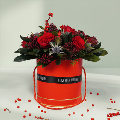 Round box Christmas flower arrangement featuring 17 to 20 roses, Ilex, Skimmia, Eryngium and Scabiosa