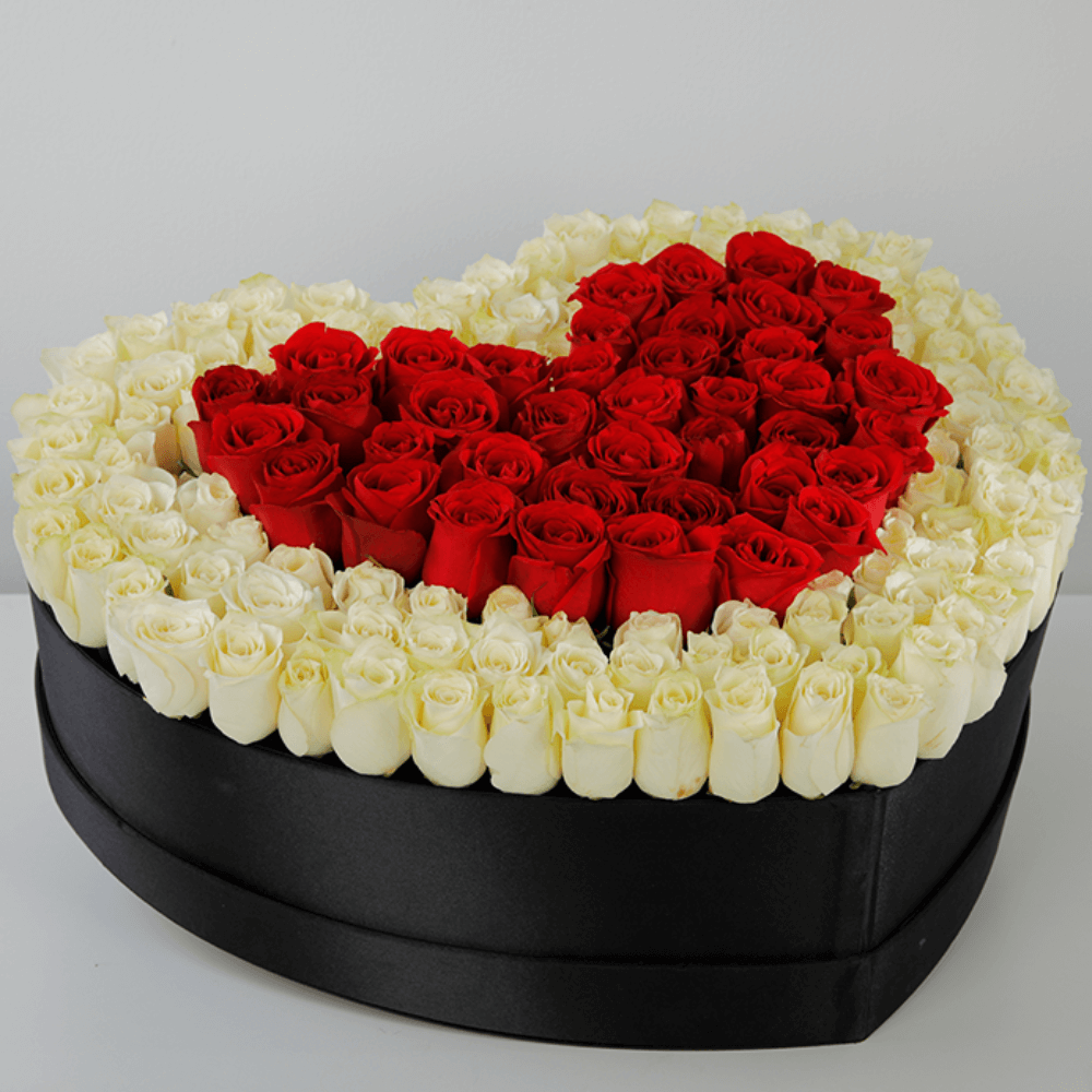 Red roses arranged in a heart shape with a white rose border inside a large black heart box