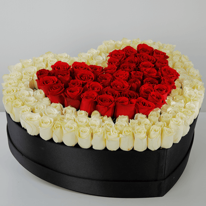 Red roses arranged in a heart shape with a white rose border inside a large black heart box