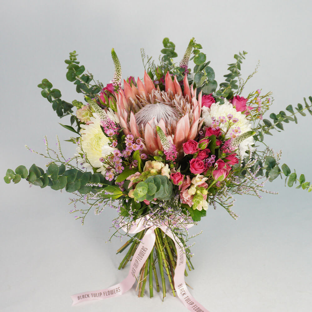 Assorted bouquet with King Protea, Spray Roses, Disbud Chrysanthemums, Veronica, Snapdragons and fresh greenery.
