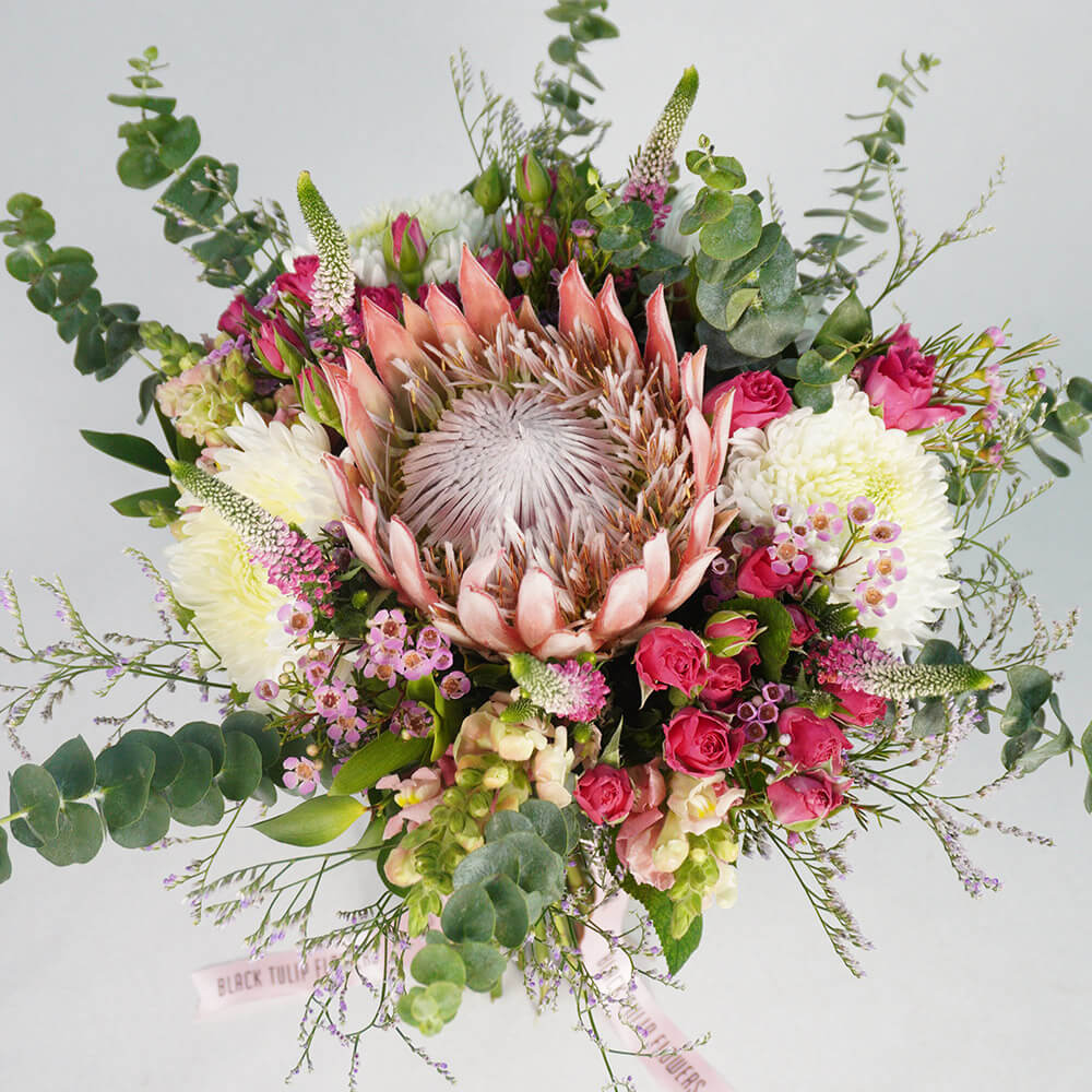 Assorted bouquet with King Protea, Spray Roses, Disbud Chrysanthemums, Veronica, Snapdragons and fresh greenery.
