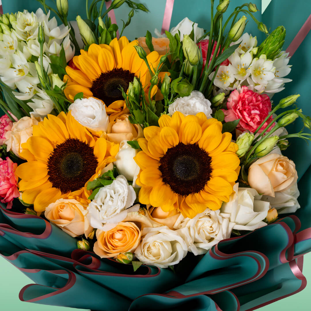 Assorted sunflower, rose, Eustoma and carnation bouquet in teal Korean wrapping