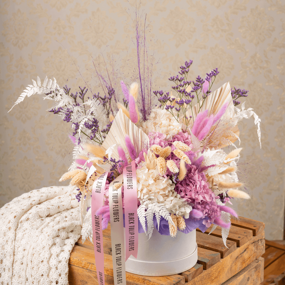 Arrangement featuring assorted dried and preserved flowers in white round box.