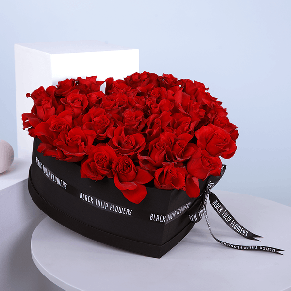 30-35 red roses arranged in a black heart-shaped flower box.