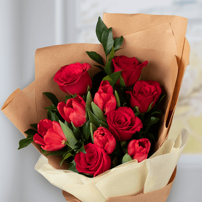 Red Tulips and Roses with greenery wrapped in brown non-woven paper.