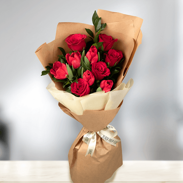Red Tulips and Roses with greenery wrapped in brown non-woven paper.