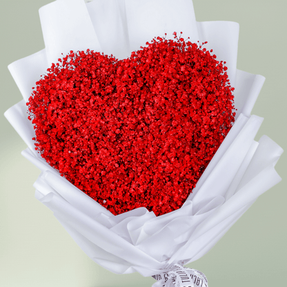 Heart shaped red flower bouquet arranged in white wrapping and finished with a ribbon.