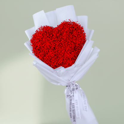 Heart shaped red flower bouquet arranged in white wrapping and finished with a ribbon.