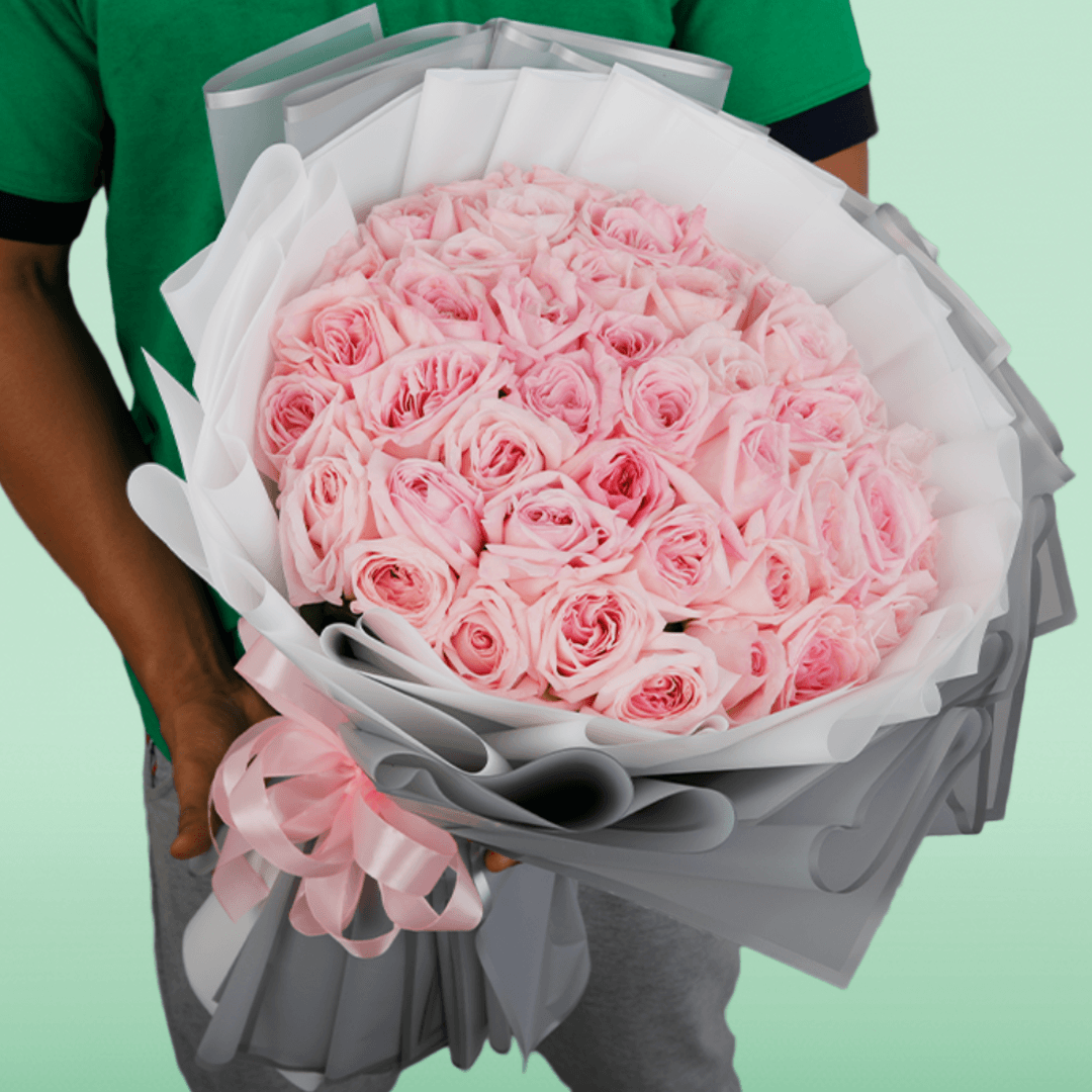 Large bouquet of 50 light pink roses in layered grey and white non-woven wrapping
