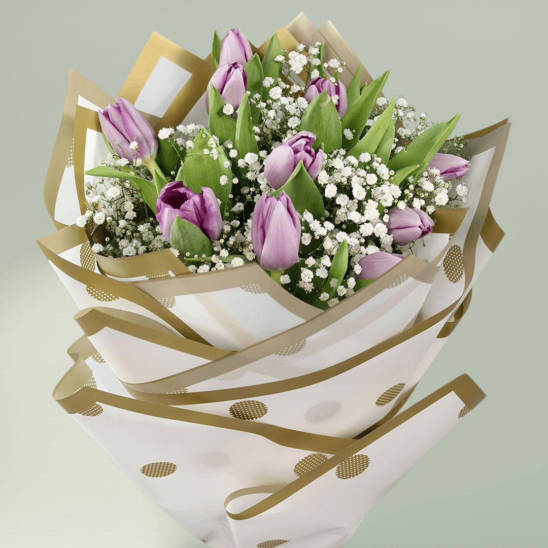 Purple tulip bouquet with baby’s breath, green foliage and elegant gold-accented wrapping.