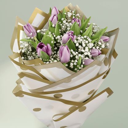 Purple tulip bouquet with baby’s breath, green foliage and elegant gold-accented wrapping.