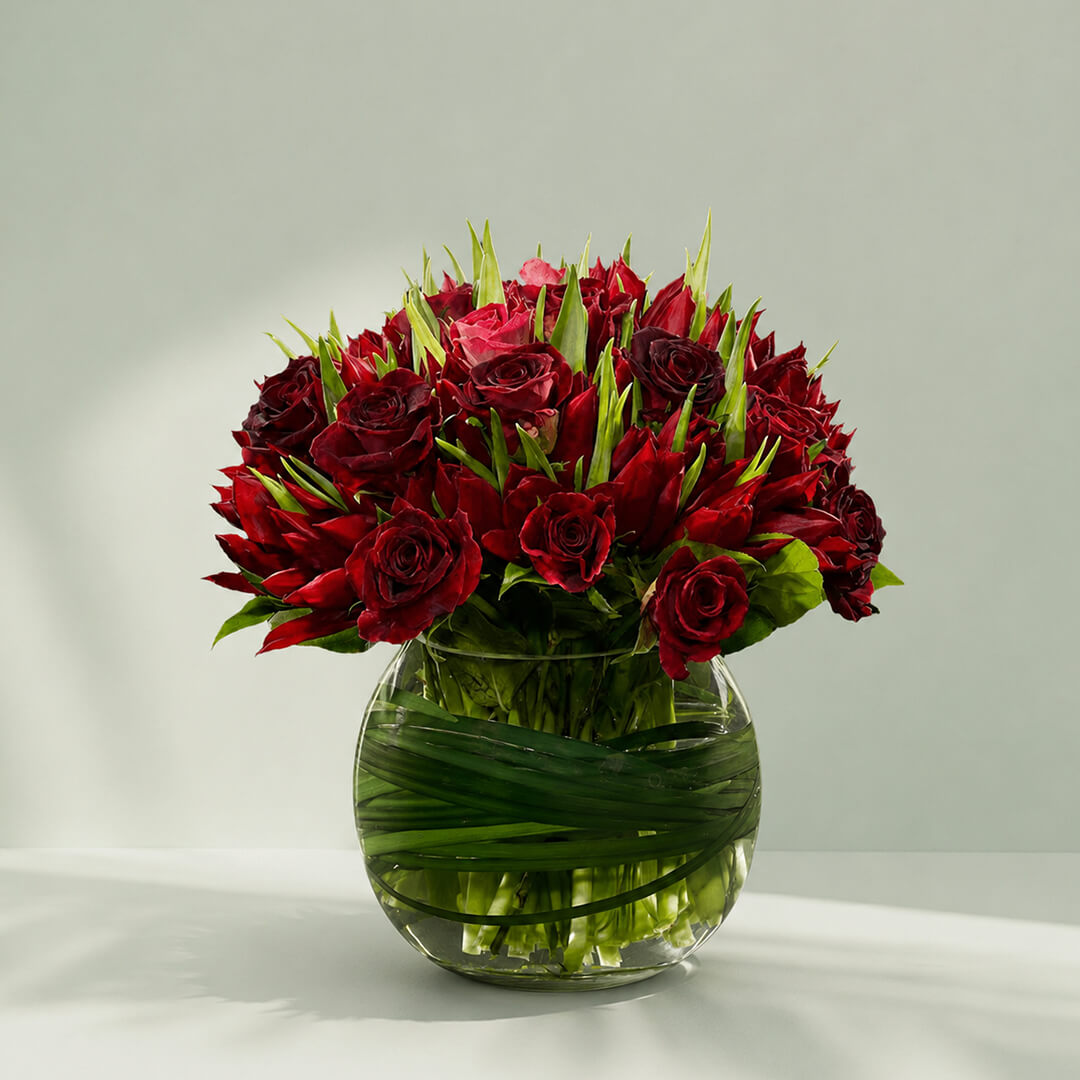 Lavish Red Tulip bouquet with red tulips and roses in glass fishbowl vase