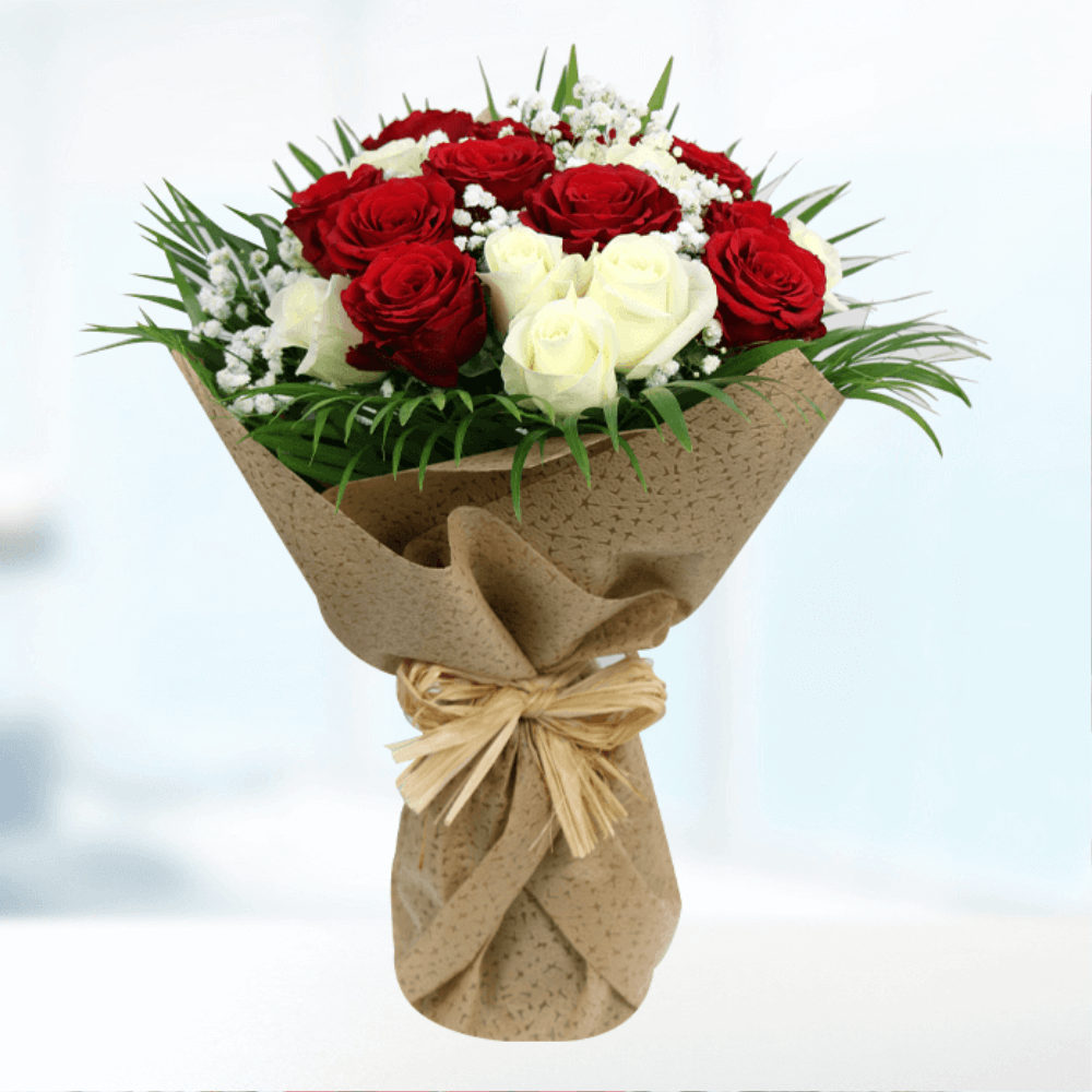 Red and white roses with fresh foliage arranged in natural brown jute wrapping

