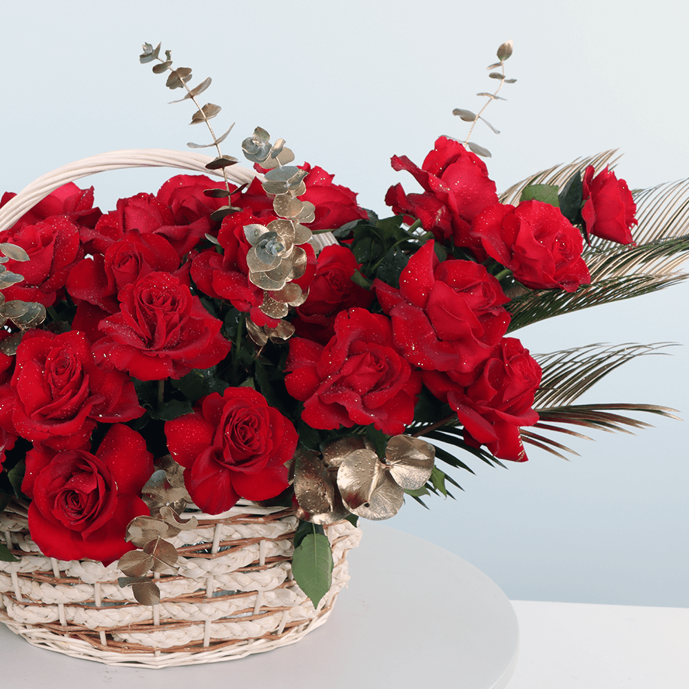 Basket arrangement of 30 red roses with Eucalyptus and decorative foliage.