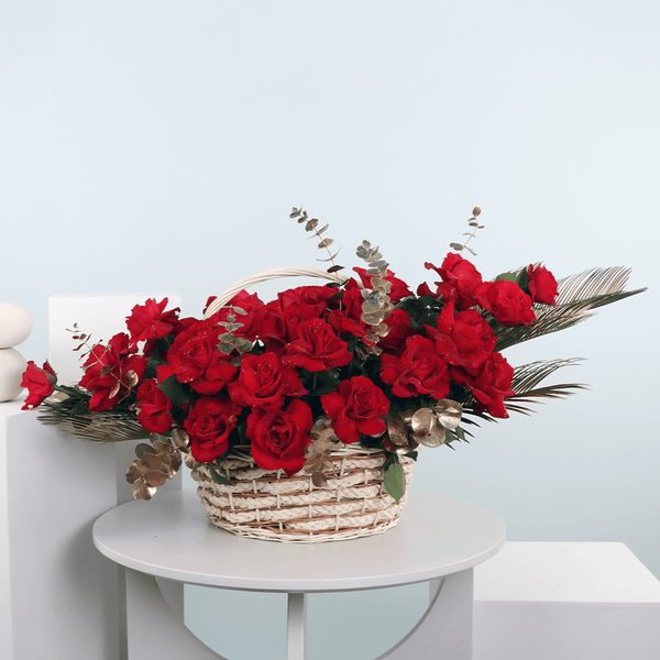 Basket arrangement of 30 red roses with Eucalyptus and decorative foliage.