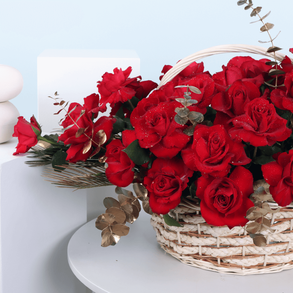 Basket arrangement of 30 red roses with Eucalyptus and decorative foliage.