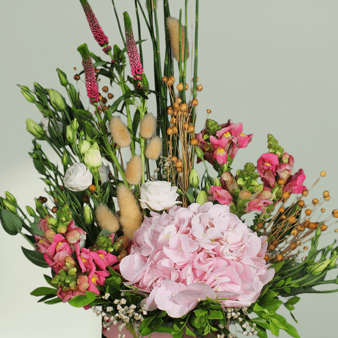 A round flower box with pink hydrangea, Eustoma, snapdragons, veronica and bunny tails.

