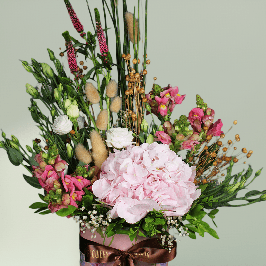 A round flower box with pink hydrangea, Eustoma, snapdragons, veronica and bunny tails.
