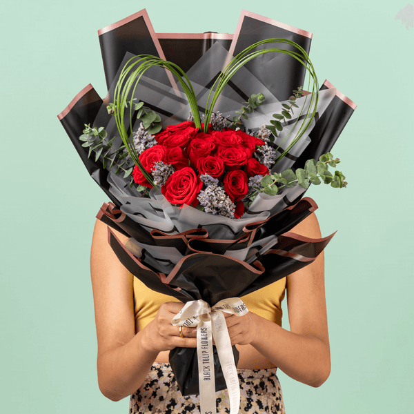 Bouquet of 25 red roses with steel grass, Limonium, and eucalyptus in black wrapping