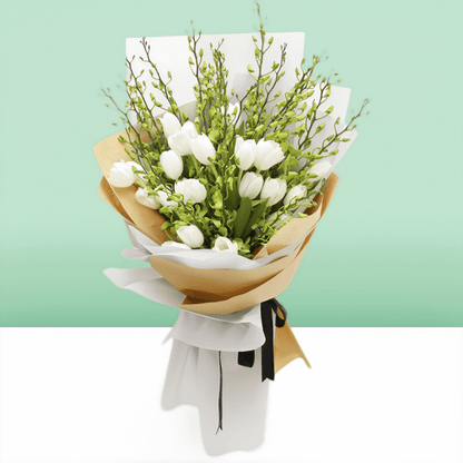 White tulips and orchid stems arranged with greenery in white and natural-toned wrapping
