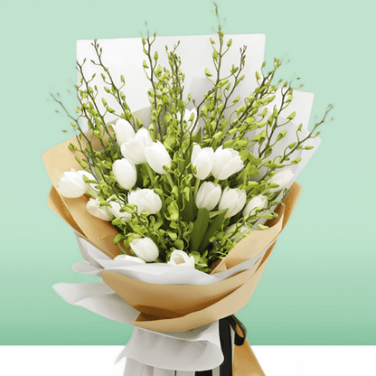 White tulips and orchid stems arranged with greenery in white and natural-toned wrapping
