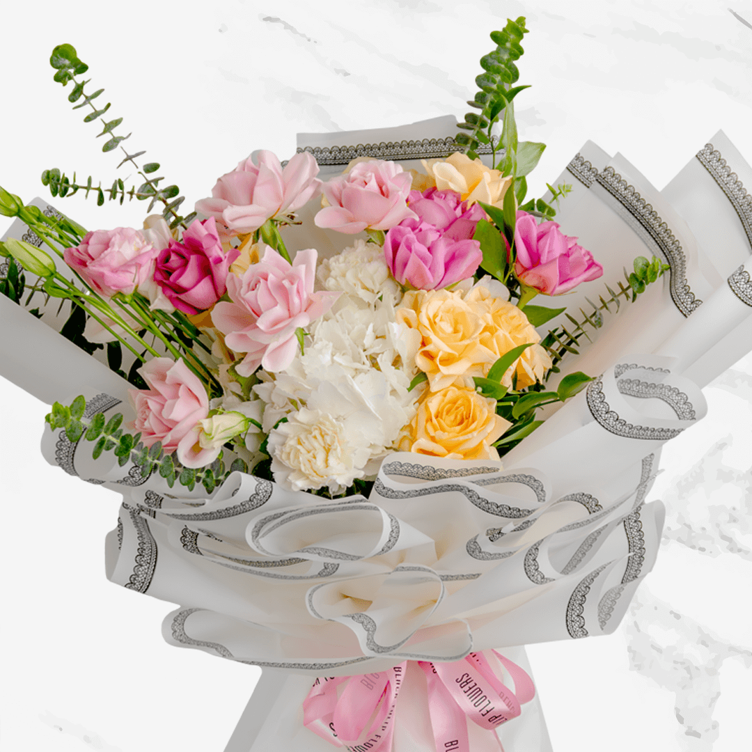 Pastel hand bouquet with pink and peach roses, white lilies, hydrangeas and eucalyptus in elegant grey wrapping.