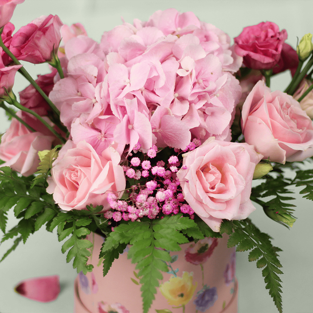 Pink Hydrangeas, Eustoma, Alstroemeria and Roses with greenery arranged in a floral-patterned round pink box.