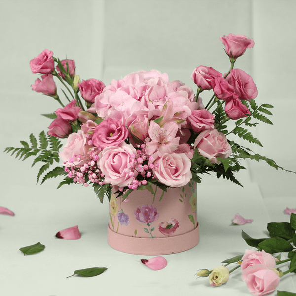 Pink Hydrangeas, Eustoma, Alstroemeria and Roses with greenery arranged in a floral-patterned round pink box.