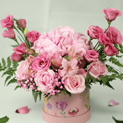 Pink Hydrangeas, Eustoma, Alstroemeria and Roses with greenery arranged in a floral-patterned round pink box.