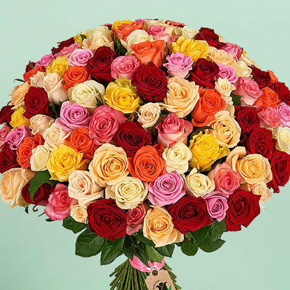 100 mixed roses bouquet in red, pink, yellow, peach, orange and cream tones, arranged in a full hand-tied style.