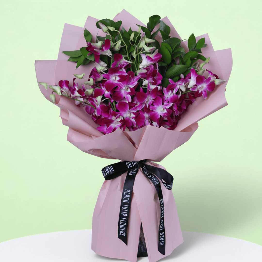 10 purple dendrobium orchids bouquet with greenery in pink wrapping and black ribbon