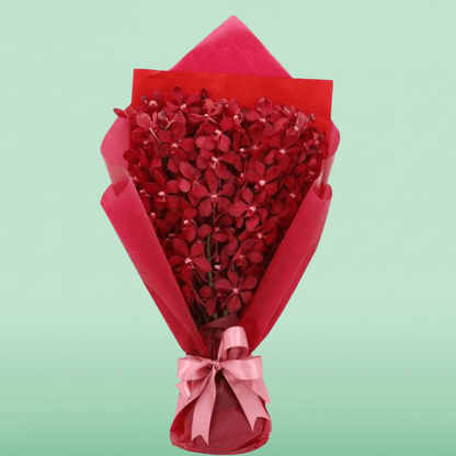 Red orchid stems arranged in layered red non-woven wrapping with a pink ribbon
