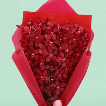 Red orchid stems arranged in layered red non-woven wrapping with a pink ribbon
