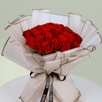 Bouquet of 35 red roses wrapped in elegant beige paper tied with black ribbon.