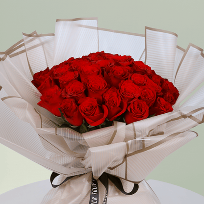 Bouquet of 35 red roses wrapped in elegant beige paper tied with black ribbon.