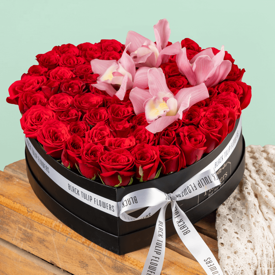 Red roses and pink cymbidium orchids in black heart box
