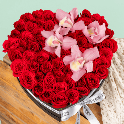 Red roses and pink cymbidium orchids in black heart box