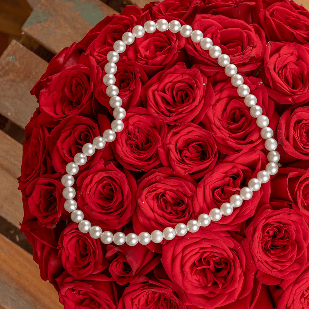 Heart-shaped flower box with 35 fresh red roses, pearl arrangement, and red ribbons.