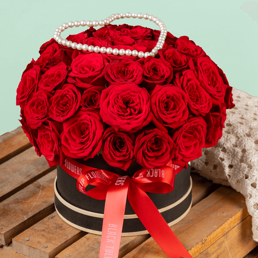 Heart-shaped flower box with 35 fresh red roses, pearl arrangement, and red ribbons.