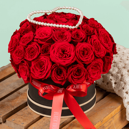 Heart-shaped flower box with 35 fresh red roses, pearl arrangement, and red ribbons.