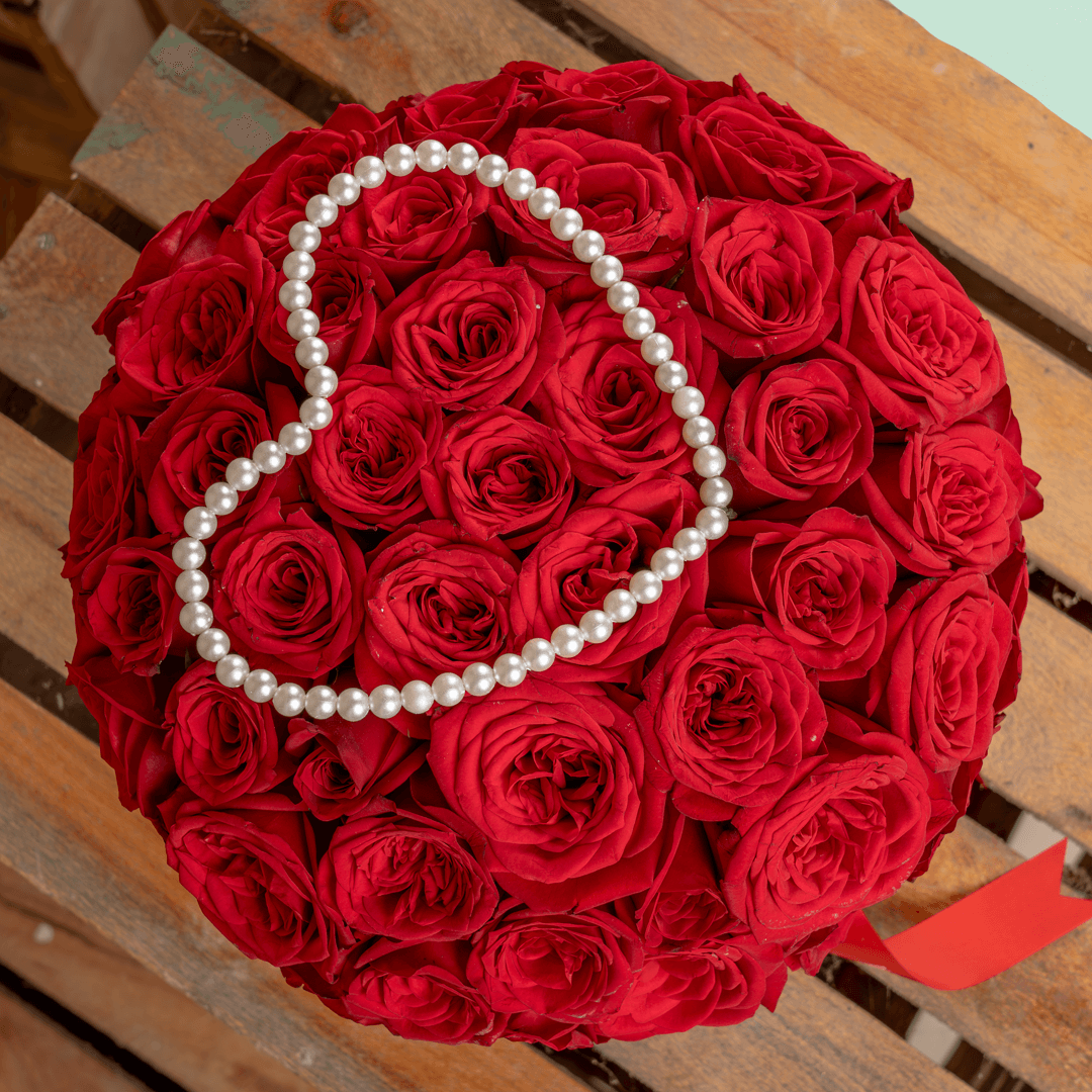 Heart-shaped flower box with 35 fresh red roses, pearl arrangement, and red ribbons.