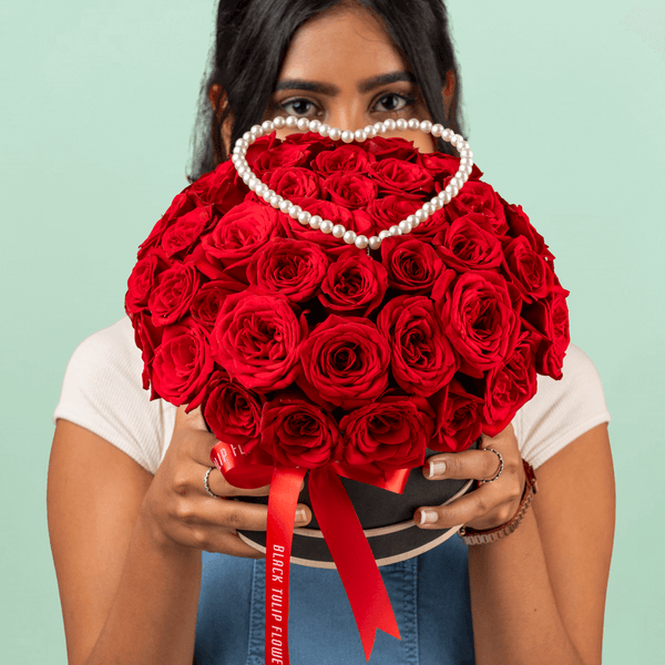 Heart-shaped flower box with 35 fresh red roses, pearl arrangement, and red ribbons.