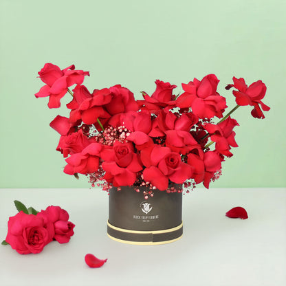 20 red Roses with Gypsophila arranged in a round grey flower box.