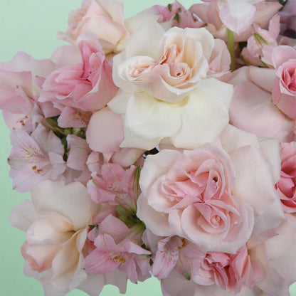 Roses, Spray Roses, Tulips and Hydrangeas with greenery arranged in a pink round flower box.