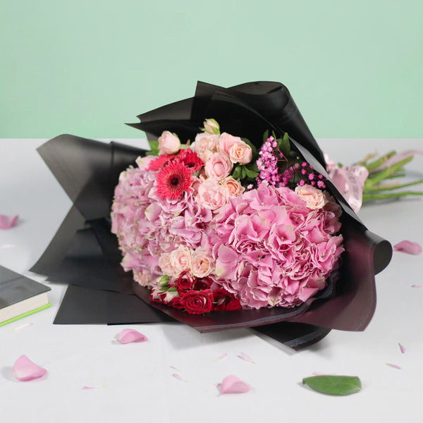 Pink Hydrangeas, Spray Roses, Gerberas and Gypsophila wrapped in black non-woven paper.