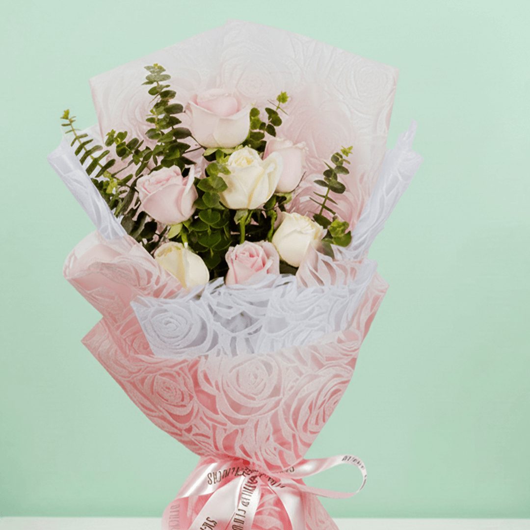 Hand -tied bouquet of pink and peach roses with eucalyptus in a pink wrap
