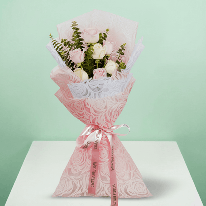 Hand -tied bouquet of pink and peach roses with eucalyptus in a pink wrap